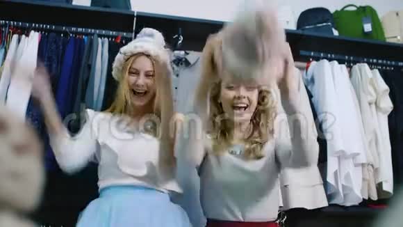 两个年轻漂亮的女人在店里玩得很开心戴帽子笑积极的情绪视频的预览图