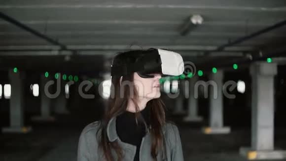年轻女子在停车处使用虚拟现实眼镜挥舞头发的女孩戴着VR耳机4K视频的预览图
