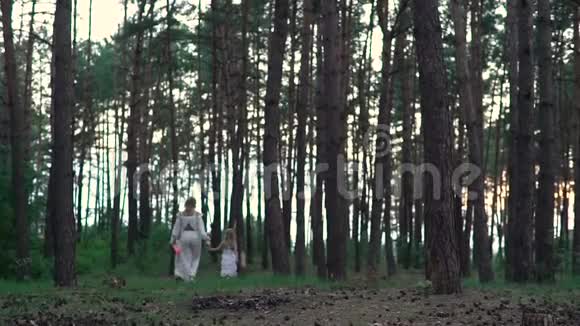 穿着白色衣服的妈妈和女儿在森林附近的田野里走来走去视频的预览图