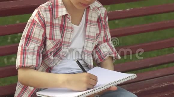 小男孩在长凳上的笔记本上画画视频的预览图