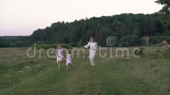 穿着白色衣服的妈妈和女儿在森林附近的田野里走来走去视频的预览图