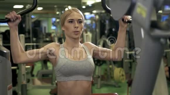 年轻健身女子在健身房用健身机进行锻炼视频的预览图