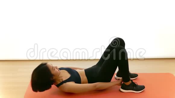 漂亮的泰国亚裔女孩正在做脚跟触摸腹肌腹部紧缩在空中有氧运动在白色背景下健身视频的预览图