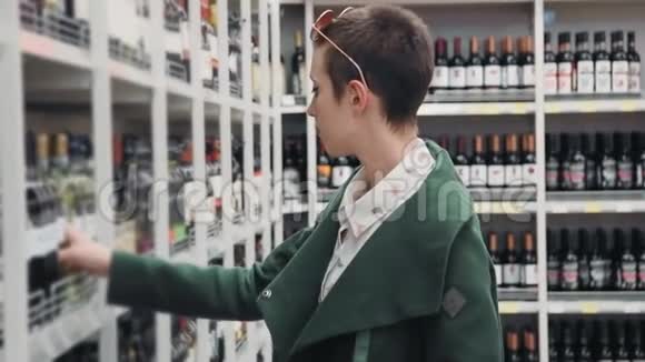 年轻的商务女性在杂货店里选择白葡萄酒瓶然后放进购物车视频的预览图