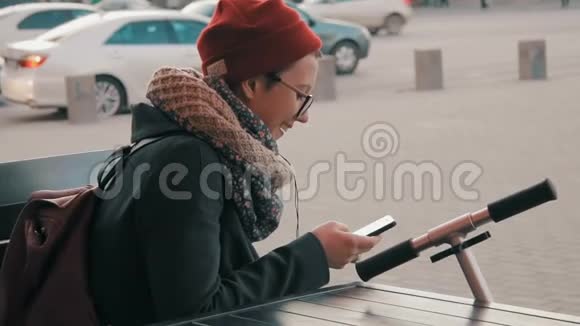 年轻的时髦女人在户外使用智能手机视频的预览图