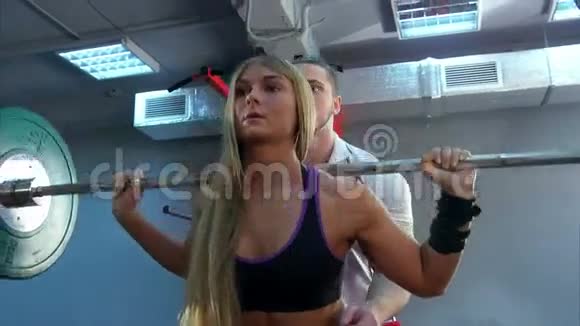 私人教练在健身房帮助女性举重视频的预览图