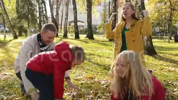 秋天公园里幸福家庭的肖像父母和孩子把橙色的叶子扔到空中视频的预览图