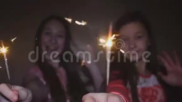 两个十几岁的女孩摆姿势用燃烧的火花笑着视频的预览图