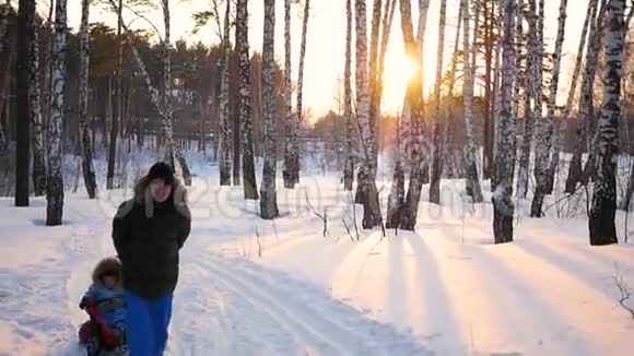 男人和孩子们玩把他们滚在雪管上下雪的冬天景观户外运动视频的预览图