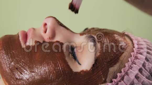 年轻漂亮的女人脸上有水疗程序巧克力温泉巧克力包装特写视频的预览图