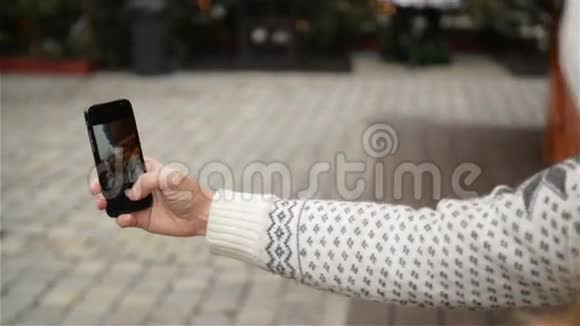 一对年轻漂亮的情侣在圣诞市场上用智能手机自拍快乐的年轻家庭视频的预览图