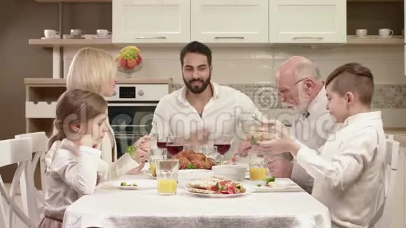 全家人围坐在餐桌旁吃饭交流和享受家庭晚餐视频的预览图