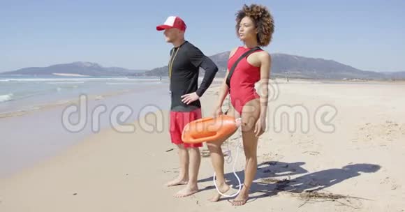 在海滩上摆姿势的男女救生员视频的预览图