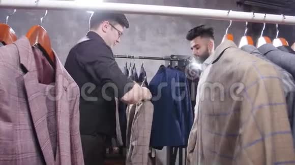 服装店的卖家帮助年轻人选择一套西装视频的预览图