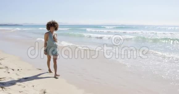 穿着连身裤的女性在沙滩上散步视频的预览图