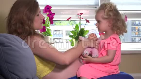 孕妇和可爱的金发女孩女儿在家玩玩具娃娃视频的预览图