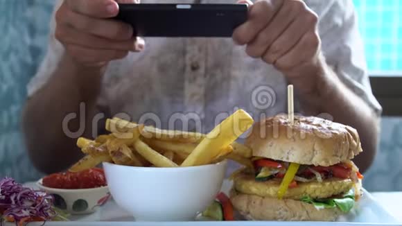男人用手机拍汉堡和炸薯条社交媒体生活方式视频的预览图