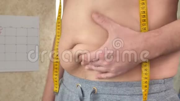 一个胖子测量他的腰部一个大啤酒肚一个健康的生活方式收集脂肪褶皱视频的预览图