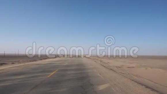 有人在空旷的沙漠道路上驾驶一辆汽车沙子随风在道路上移动的观点视频的预览图