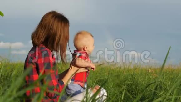 快乐的年轻母亲在阳光温暖的秋日或夏日与她的小儿子玩耍天空中的彩虹快乐视频的预览图