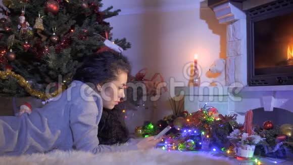 圣诞树和壁炉附近有电话的美女视频的预览图