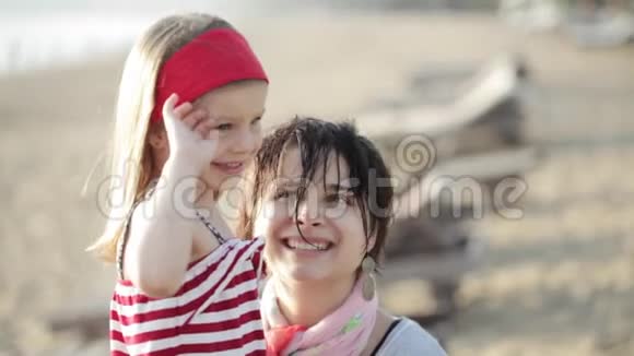 永妈妈带着小女儿微笑拥抱在沙滩上视频的预览图