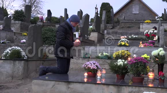 悲伤的人用蜡烛跪在墓地的大理石墓碑上4K视频的预览图
