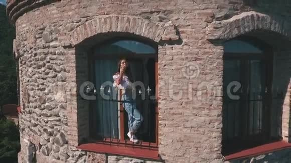 美丽的年轻女子从城堡的窗户挥手视频的预览图