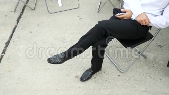 男人经典的黑鞋那个人坐在椅子上拿着电话4k视频的预览图