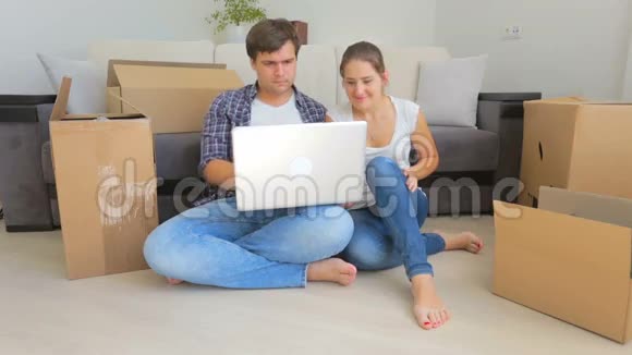 快乐的年轻夫妇在他们的新家拆箱选择笔记本电脑家具视频的预览图