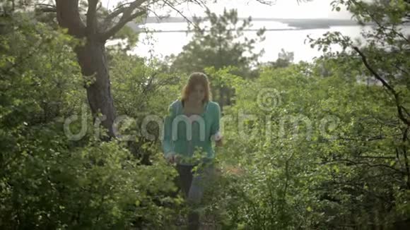 年轻漂亮的女人在森林里的树间散步夏季景观视频的预览图