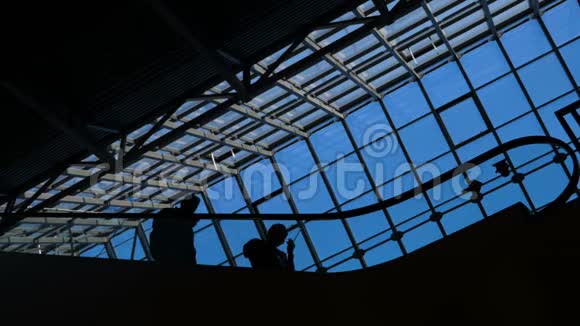 现代玻璃建筑和扶梯上商务人士的移动轮廓视频的预览图