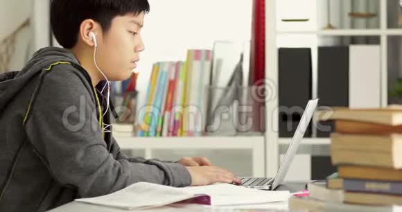 可爱的亚洲少年在家用笔记本电脑做作业视频的预览图