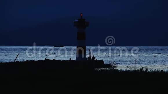 日落时华盛顿海岸北头灯塔的灯光照耀用鱼竿捕鱼的渔民视频的预览图