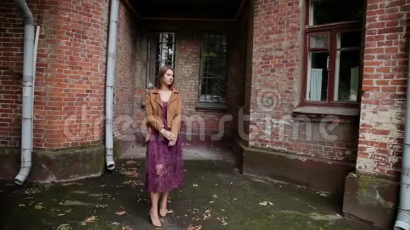 在砖房的老院子里摆姿势的漂亮女孩视频的预览图