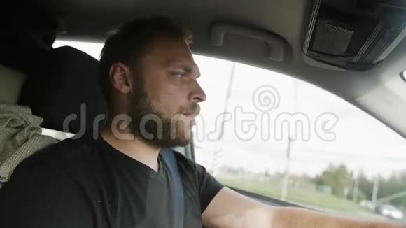 开车的人英俊的留着胡子的男人穿着黑色T恤开车开车旅行视频的预览图