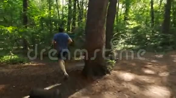 成年男子在森林小径上的森林大自然中慢跑享受它看上去很快乐视频的预览图