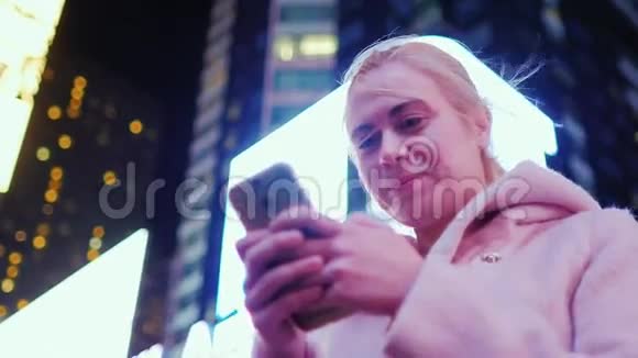 纽约时代广场夜晚摩天大楼背景下一位年轻白种人妇女的肖像微笑享受视频的预览图