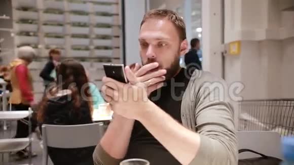 感到惊讶男人正在情绪化地看着他的智能手机男人的脸男人把手放在脸上视频的预览图