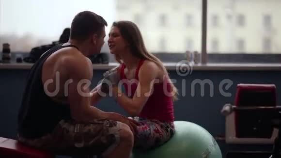 恋人们一起工作女人在做新闻练习时亲吻她的男人他帮助她在健身房锻炼视频的预览图