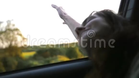 看女人的手在玩风把手举起来夏天坐汽车的年轻女子风吹头发慢节奏视频的预览图