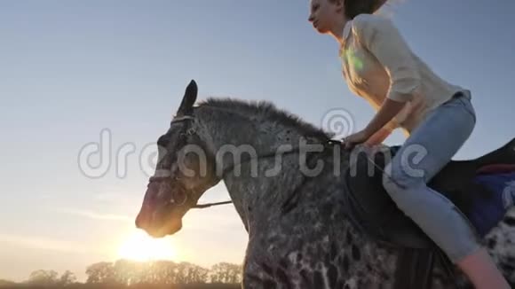 日落时骑在草地上的小女孩的超慢动作视频的预览图