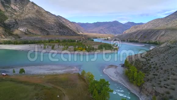 一条蓝色河流在山谷中流动的空中镜头视频的预览图