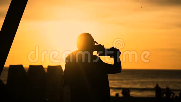 日落时分站在沙滩上自拍照片的人剪影视频的预览图