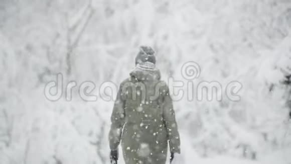 年轻美丽的白种人女孩穿着夹克走在冬天的森林在雪天慢动作慢动作视频的预览图