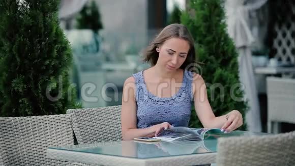 女孩拿起一本杂志开始打开它视频的预览图