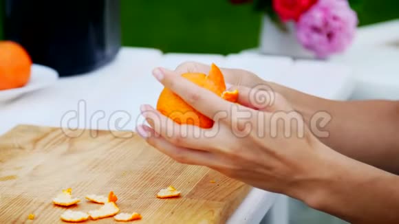 夏天在花园里特写镜头雌性的手在剥一个橘子皮家庭假日自然午餐视频的预览图