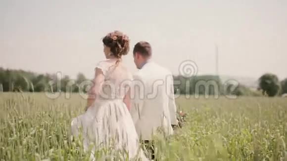 在婚礼那天一对相爱的夫妇在麦田里牵手散步漂亮的结婚礼服视频的预览图