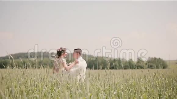 在夏天的婚礼上一对美丽的恋人站在麦田里新郎新娘拥抱亲吻视频的预览图