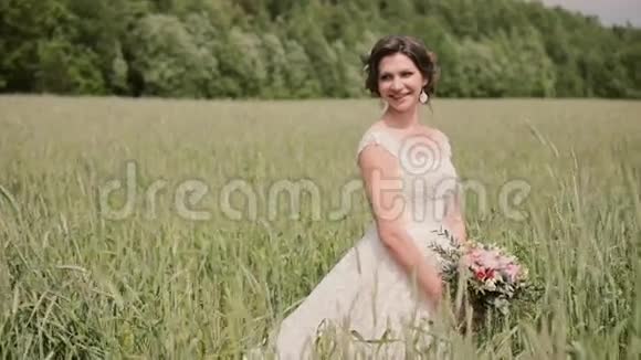 美丽的微笑新娘在麦田里享受她的婚礼头发和锥在风中摇摆视频的预览图